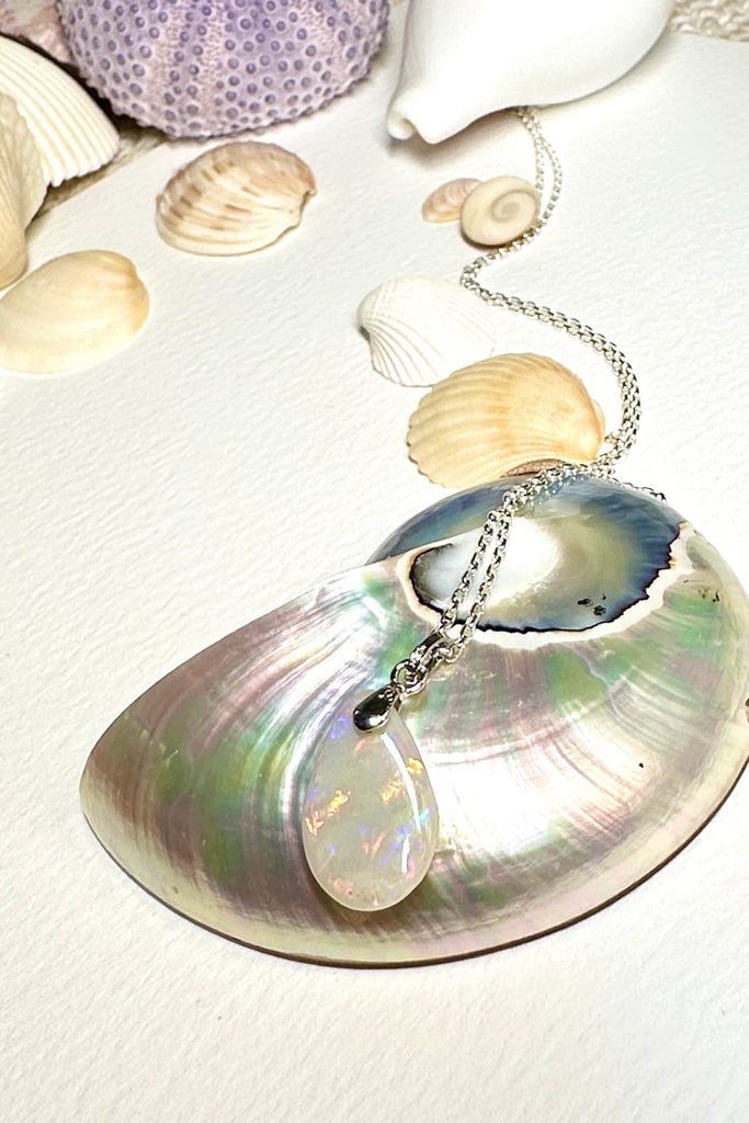 This soft droplet shaped opal pendant has fiery gold and red flashes in the pale silvery grey base, 