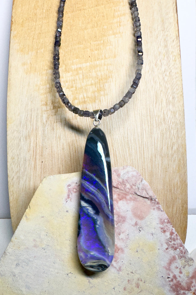 This black Opal pendant is an absolute stunner, a wonderous slice of opal heaven, black and grey base with bright purple and blue crystal swirling across and white clouds as a highlight.