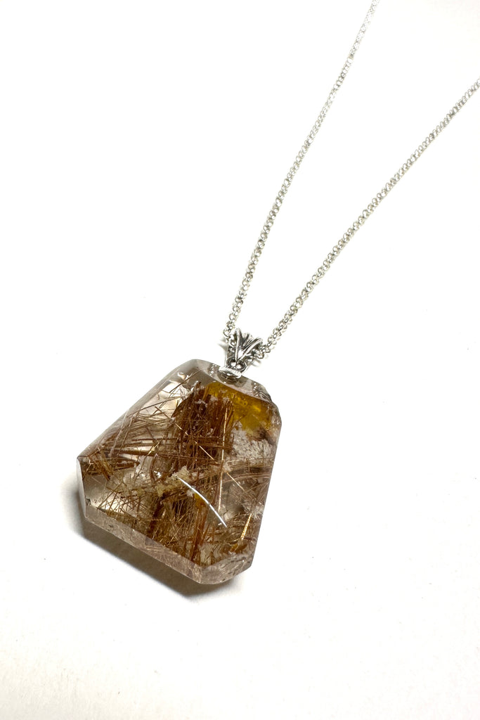 natural crystal pendant polished to a high shine, this stone is cut into a strong oval shape with the Rutile needles dense throughout