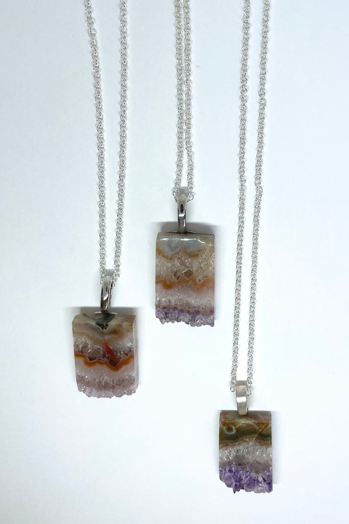 An Amethyst druzy crystal, cut as a slice with the crystals at the base. It hangs from a  silvery chain. A lovely bohemian luxe chic necklace.