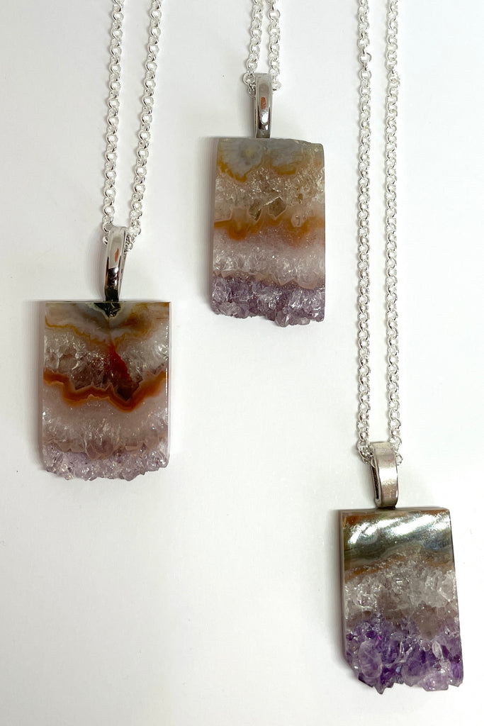 An Amethyst druzy crystal, cut as a slice with the crystals at the base. It hangs from a  silvery chain. A lovely bohemian luxe chic necklace.