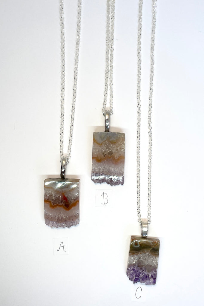 An Amethyst druzy crystal, cut as a slice with the crystals at the base. It hangs from a  silvery chain. A lovely bohemian luxe chic necklace.