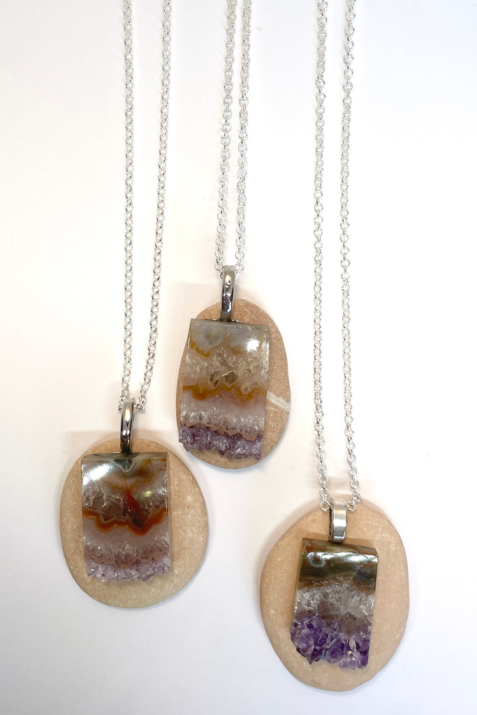 An Amethyst druzy crystal, cut as a slice with the crystals at the base. It hangs from a  silvery chain. A lovely bohemian luxe chic necklace.