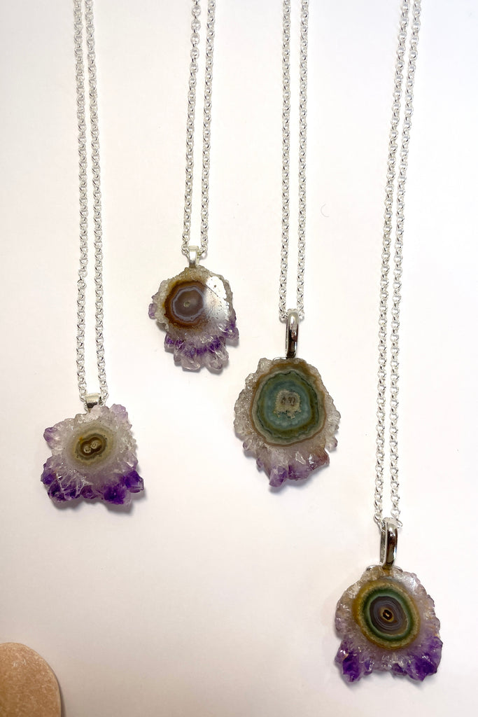 A lovely Amethyst druzy flower, pendant, cut as a slice with the crystal formations in the centre and the purple crystals at the base. It hangs from a  silvery chain. 