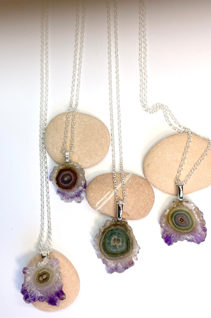 A lovely Amethyst druzy flower, pendant, cut as a slice with the crystal formations in the centre and the purple crystals at the base. It hangs from a  silvery chain. 