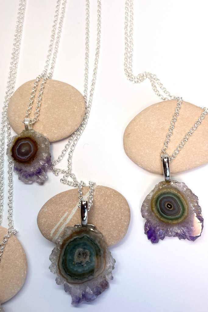 A lovely Amethyst druzy flower, pendant, cut as a slice with the crystal formations in the centre and the purple crystals at the base. It hangs from a  silvery chain. 
