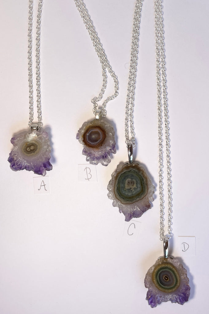 A lovely Amethyst druzy flower, pendant, cut as a slice with the crystal formations in the centre and the purple crystals at the base. It hangs from a  silvery chain. 