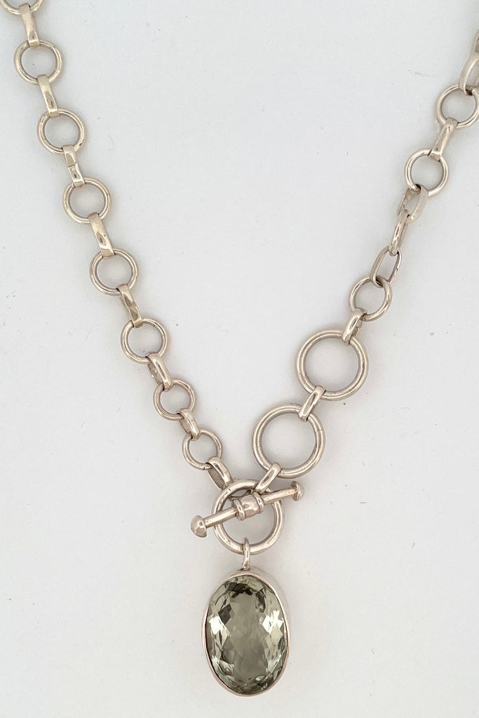 This lovely pale green faceted gemstone is beautifully faceted on both sides, set with an open back to let light in. The chain is heavy silver in choker length.