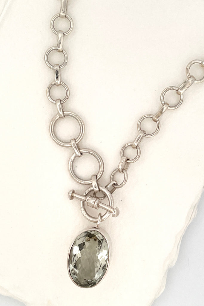 This lovely pale green faceted gemstone is beautifully faceted on both sides, set with an open back to let light in. The chain is heavy silver in choker length.