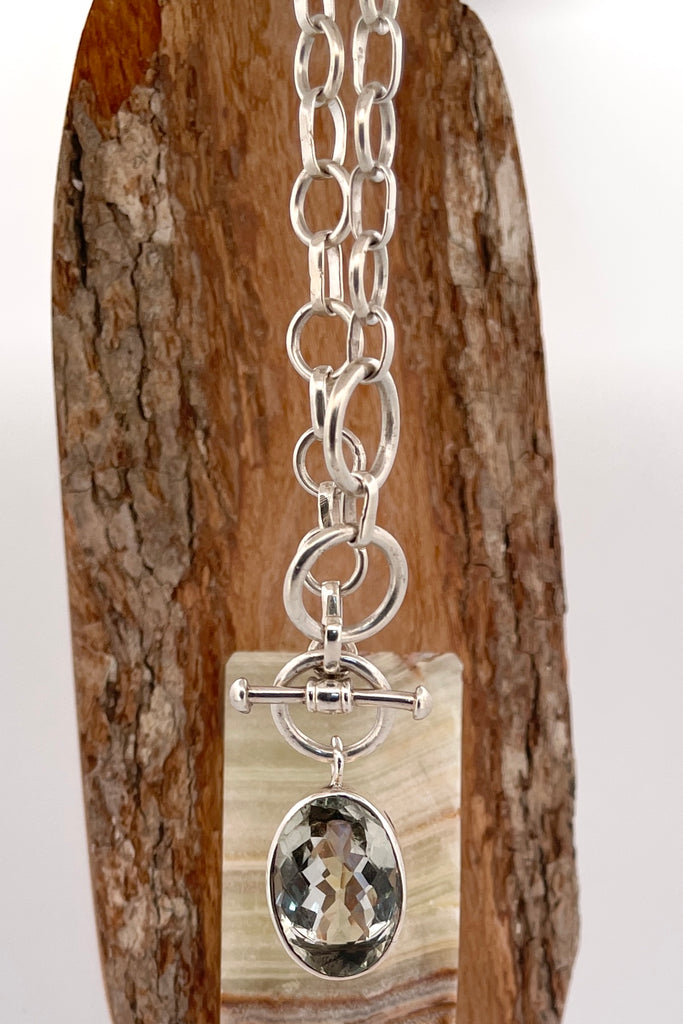 This lovely pale green faceted gemstone is beautifully faceted on both sides, set with an open back to let light in. The chain is heavy silver in choker length.