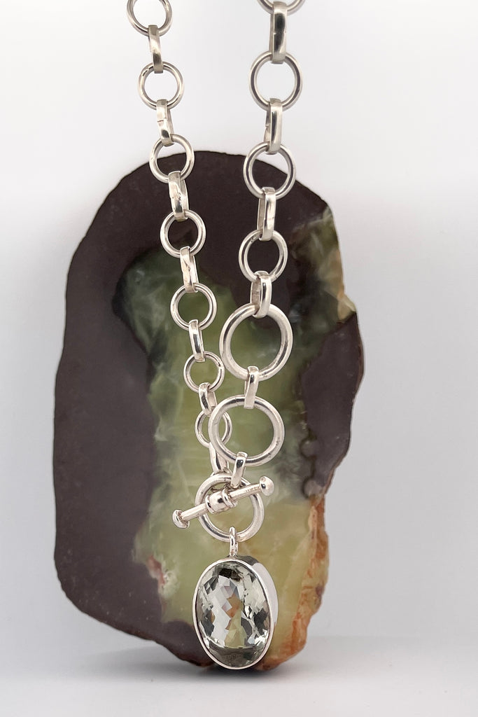 This lovely pale green faceted gemstone is beautifully faceted on both sides, set with an open back to let light in. The chain is heavy silver in choker length.