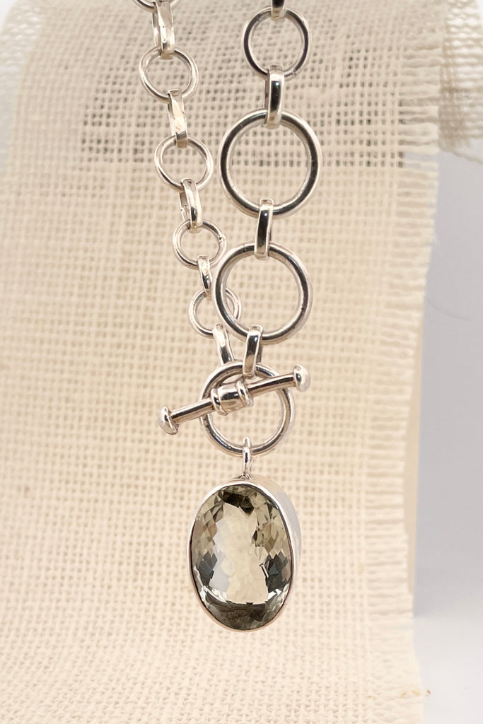 This lovely pale green faceted gemstone is beautifully faceted on both sides, set with an open back to let light in. The chain is heavy silver in choker length.