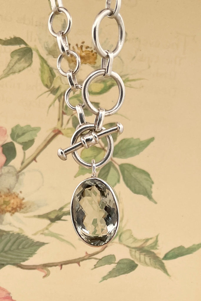 This lovely pale green faceted gemstone is beautifully faceted on both sides, set with an open back to let light in. The chain is heavy silver in choker length.
