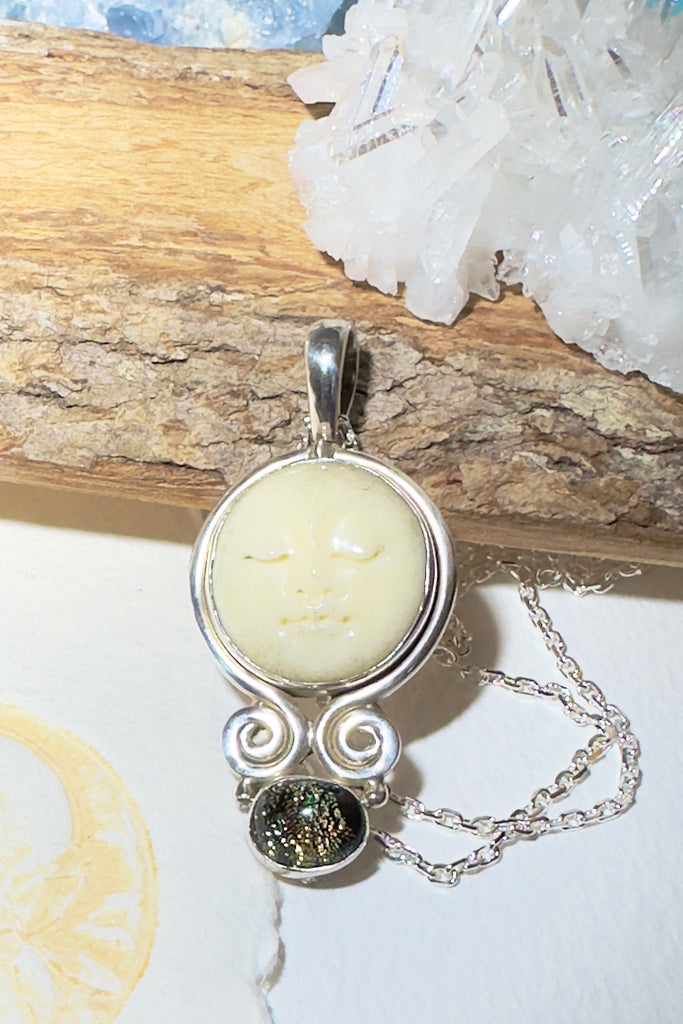 This calm and beautiful hand carved Goddess face has been set in 925 silver, At the base is a Dichroic glass droplet.