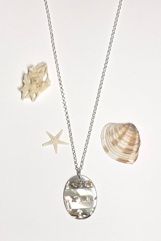 This oval shaped shell pendant has been inlaid with different colours of sea shell.