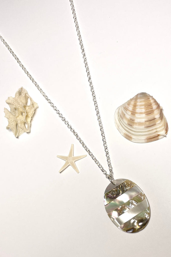 This oval shaped shell pendant has been inlaid with different colours of sea shell.
