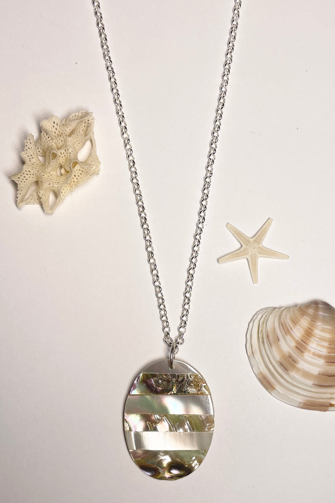 This oval shaped shell pendant has been inlaid with different colours of sea shell.