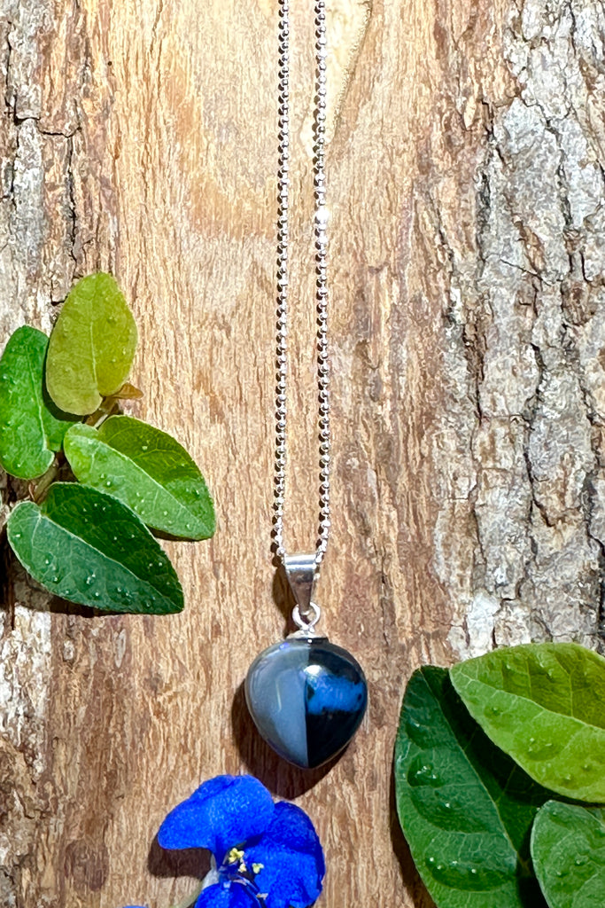 This unique black opal is divided by a tiny crystal window straight down the centre, one side is silvery grey the other black with a soft blue pool of colour. Its full of intrigue.
