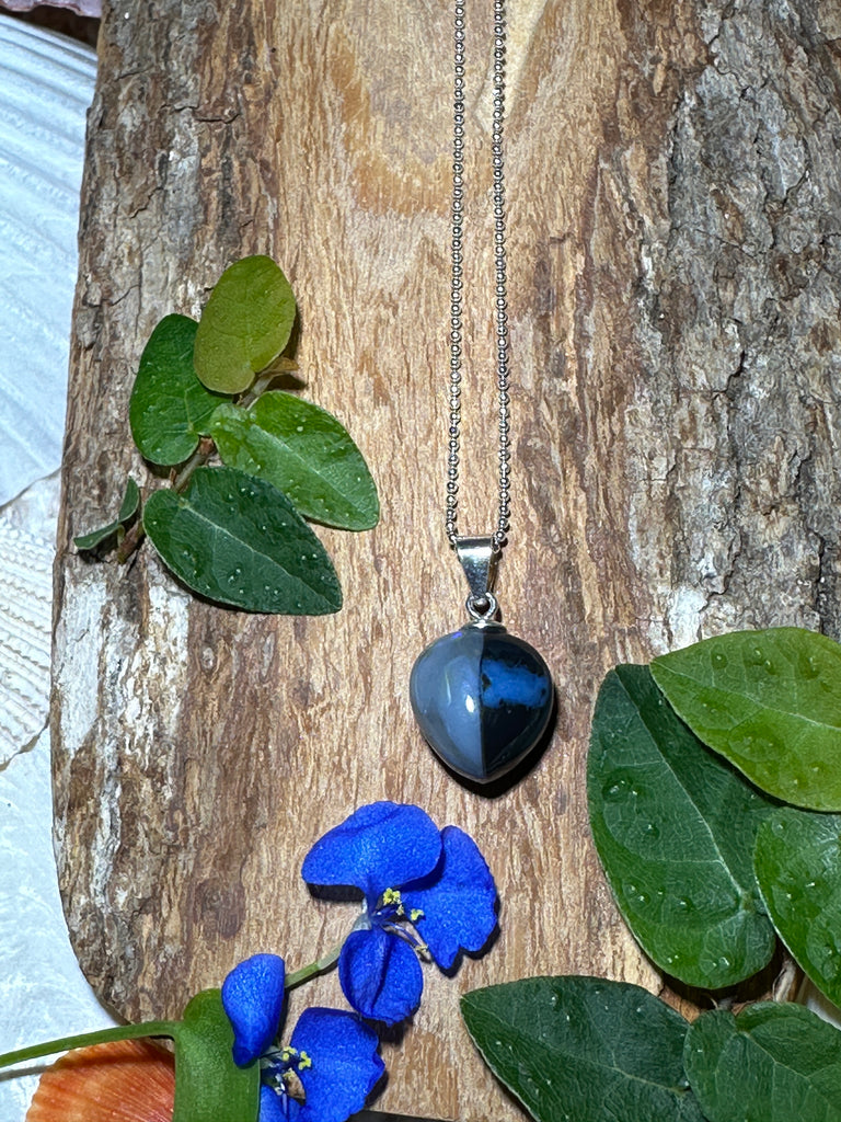 This unique black opal is divided by a tiny crystal window straight down the centre, one side is silvery grey the other black with a soft blue pool of colour. Its full of intrigue.