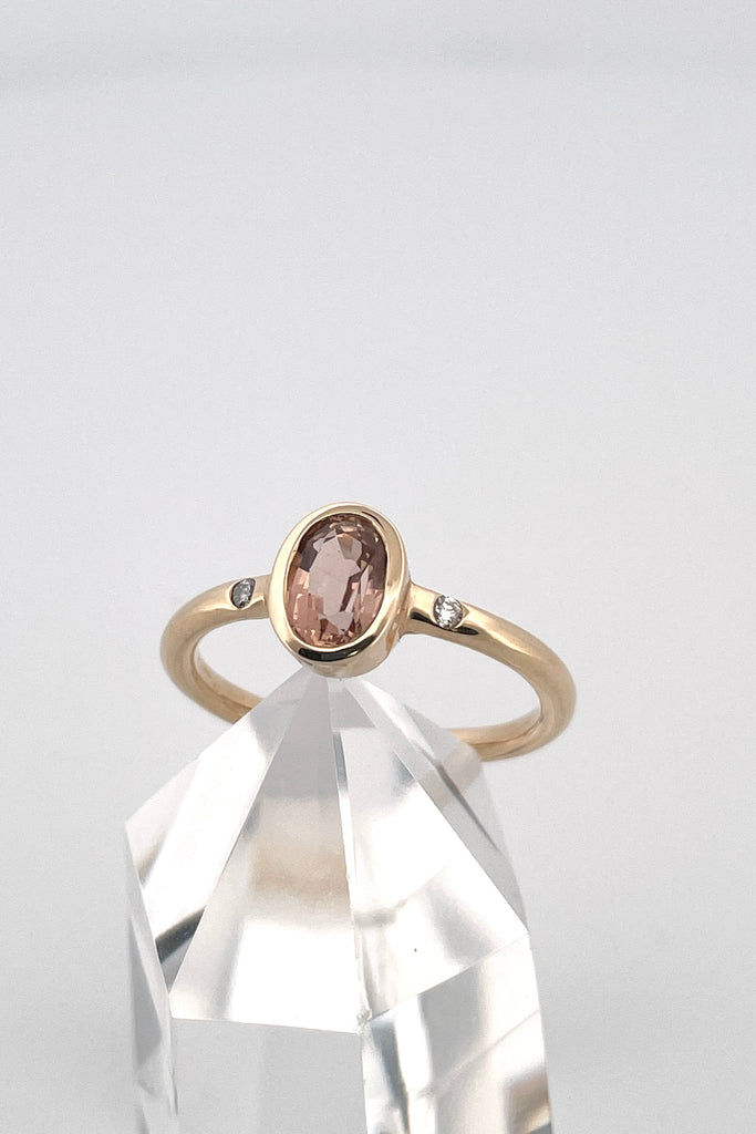 A beautiful simple ring designed to complement the lovely natural pale peach pink tourmaline gemstone set into the ring. The shank of the ring has a diamond on each side of the centre stone. 
