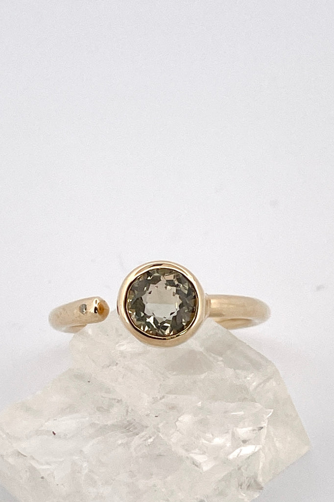 a unique modern style all of its own this stunning 10k gold ring is set with a beautiful untreated soft yellow Nigerian Tourmaline offset by a sparkling 1pt Diamond. The setting features a band that ends before the stone, leaving a tiny gap enhanced with a diamond.