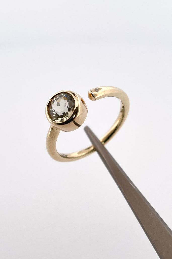 a unique modern style all of its own this stunning 10k gold ring is set with a beautiful untreated soft yellow Nigerian Tourmaline offset by a sparkling 1pt Diamond. The setting features a band that ends before the stone, leaving a tiny gap enhanced with a diamond.