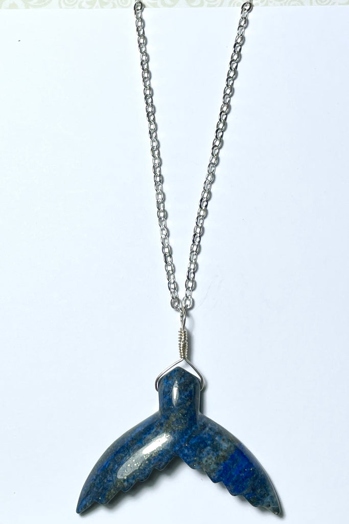 This Lapis Lazuli pendant has a centre piece which is a hand cut and carved into the shape of a whale tail.  
