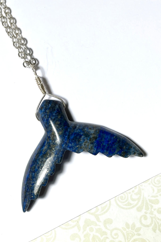 This Lapis Lazuli pendant has a centre piece which is a hand cut and carved into the shape of a whale tail.  