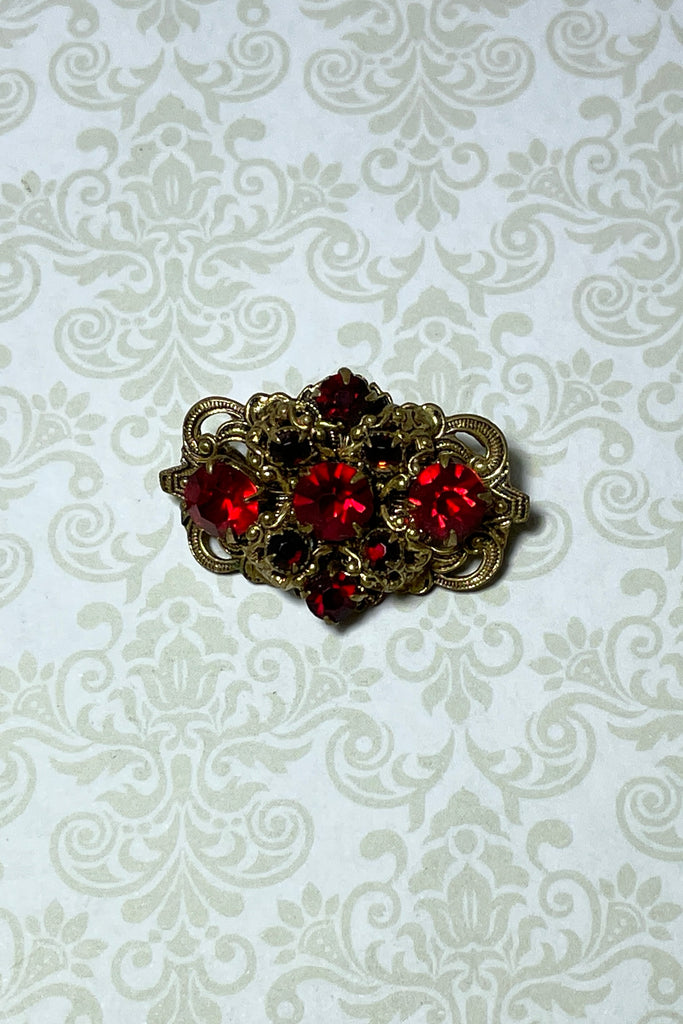 A tiny Edwadian 1910s brooch with antique gold metal set with bright red rhinestones. Such an elegant pop of colour. Condition is very good on the front, the clasp however is a bit loose.