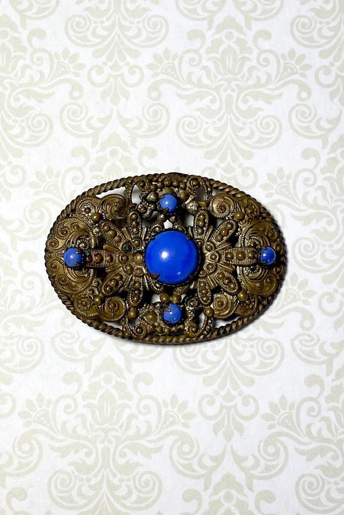 From the Edwardian era, it features a bright blue glass cabochon in the centre and four smaller blue stones that are all claw set with none missing.