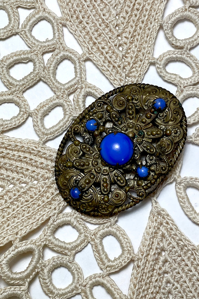 From the Edwardian era, it features a bright blue glass cabochon in the centre and four smaller blue stones that are all claw set with none missing.