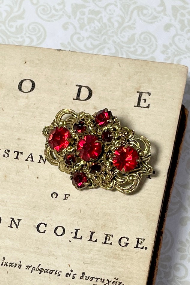 A tiny Edwadian 1910s brooch with antique gold metal set with bright red rhinestones. Such an elegant pop of colour. Condition is very good on the front, the clasp however is a bit loose.