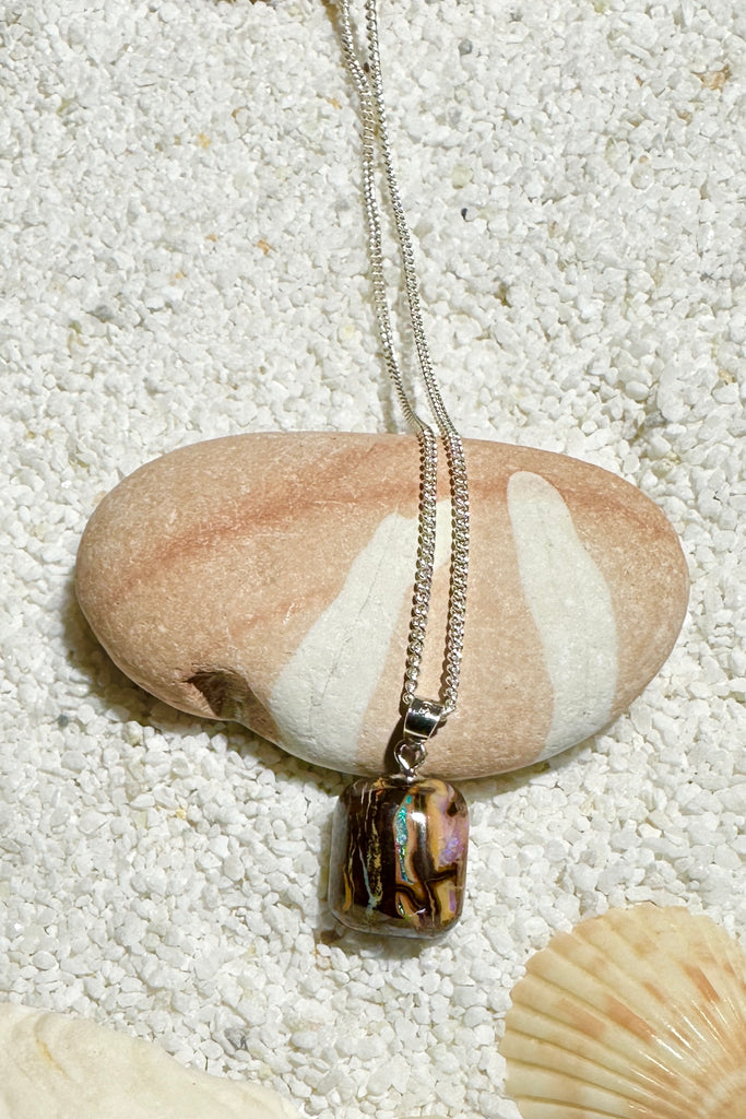 An Australian opal pendant in the colours of the desert and two tiny rivers of teal blue green deep through the stone with some mauve crystals on the side.