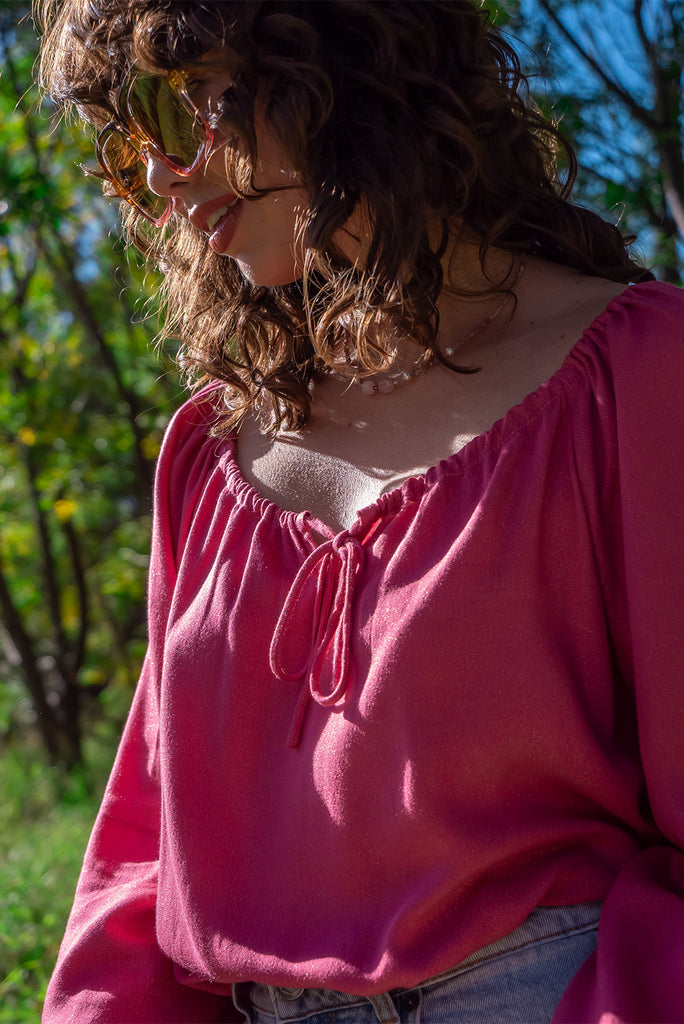 The Joni Berry Sparkle Boho Blouse is a beautiful deep pink blouse with a gold lurex shimmer all throughout. The blouse features a drawstring neckline with front keyhole and long sleeves with elasticated cuffs. Made from a woven blend of rayon, lurex, mulberry silk, and modal.