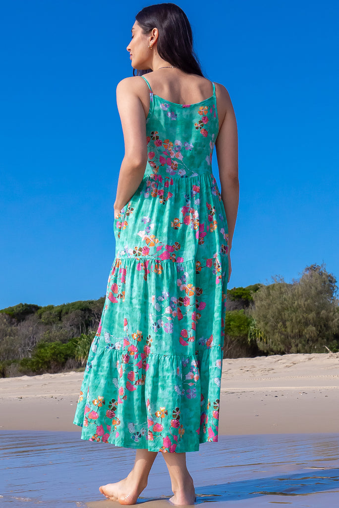 The Le Lagon Green Sea Glass Maxi Dress is a gorgeous sea green maxi dress with a green wash effect base and botanical print. The dress features silver heart beads on the shoulder straps, tiered skirting and side pockets. Made from a woven blend of cotton and rayon.