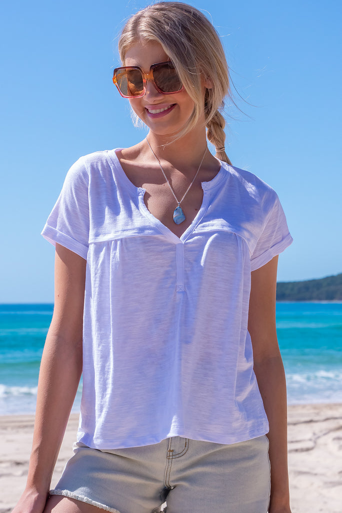 The Lei Tee Bright White Shirt is beautiful white t-shirt. The tee features a split neckline, rolled sleeve cuffs, and a gathered bust panel. Made from knit cotton.