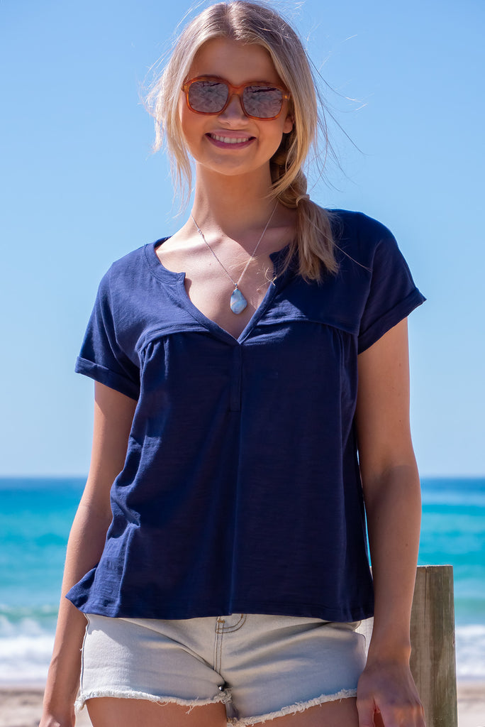 The Lei Tee Midnight Sail Shirt is beautiful navy blue t-shirt. The tee features a split neckline, rolled sleeve cuffs, and a gathered bust panel. Made from knit cotton.