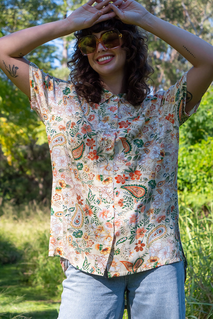 The Leonora The Florist Shirt is a gorgeous pale yellow button up shirt with a floral paisley print. The blouse features short sleeves, button down front, classic collar, one bust pocket, side slits, scooped hem at sides and slightly longer back. Made from woven 100% rayon.
