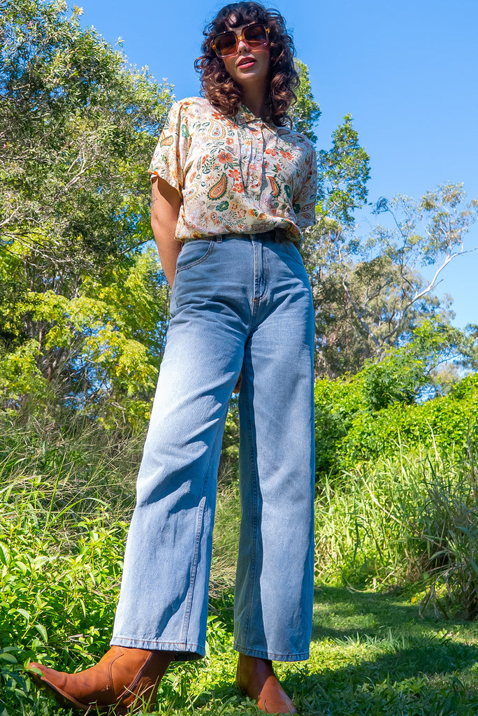 The Leonora The Florist Shirt is a gorgeous pale yellow button up shirt with a floral paisley print. The blouse features short sleeves, button down front, classic collar, one bust pocket, side slits, scooped hem at sides and slightly longer back. Made from woven 100% rayon.