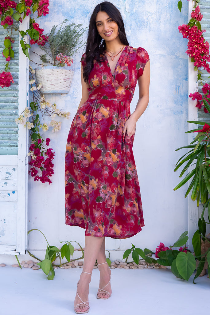 The Lizzie Artista Red Midi Dress is a beautiful red based dress with a watercolour floral print. The dress features cap sleeves, a deep v neckline, fitted Basque waist with gathered bust, elastic shirring at back waist, side pockets and is made from woven 100% rayon.