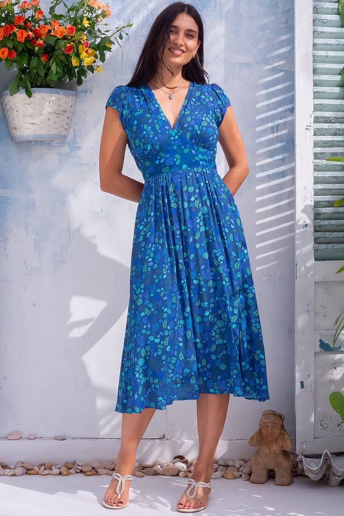 The Lizzie Sea Shells Blue Midi Dress is a beautiful blue midi dress with a cool toned small shell print all over. The dress features a basque waist, feminine cut and gathered bust. Made from 100% rayon.  