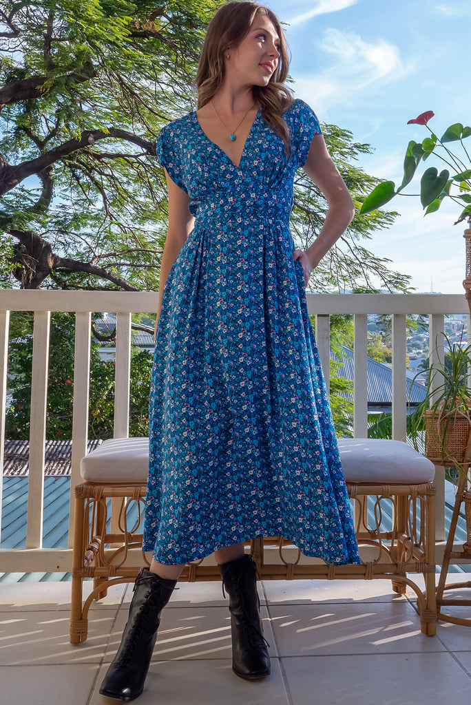The Lizzie Blue Tea Rose Dress is a beautiful black dress with a blue ditty floral print. The dress features cap sleeves, a deep v neckline, fitted Basque waist with gathered bust, elastic shirring at back waist, side pockets and is made from woven 100% rayon.