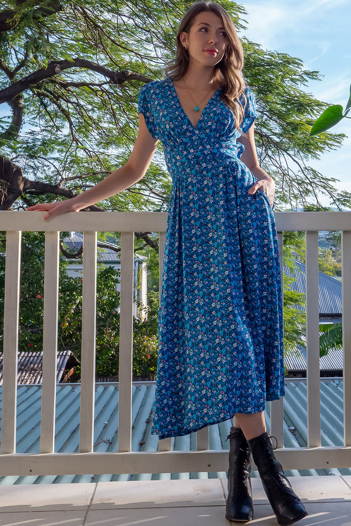 The Lizzie Blue Tea Rose Dress is a beautiful black dress with a blue ditty floral print. The dress features cap sleeves, a deep v neckline, fitted Basque waist with gathered bust, elastic shirring at back waist, side pockets and is made from woven 100% rayon.