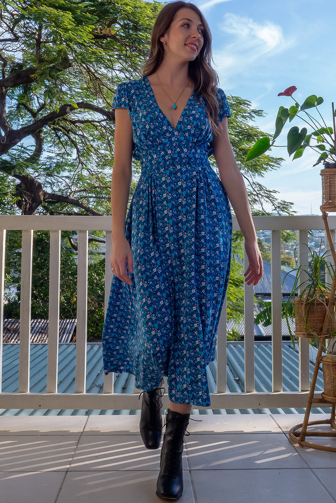 The Lizzie Blue Tea Rose Dress is a beautiful black dress with a blue ditty floral print. The dress features cap sleeves, a deep v neckline, fitted Basque waist with gathered bust, elastic shirring at back waist, side pockets and is made from woven 100% rayon.