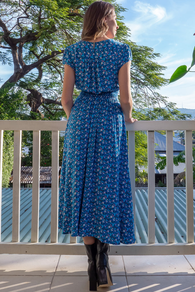 The Lizzie Blue Tea Rose Dress is a beautiful black dress with a blue ditty floral print. The dress features cap sleeves, a deep v neckline, fitted Basque waist with gathered bust, elastic shirring at back waist, side pockets and is made from woven 100% rayon.