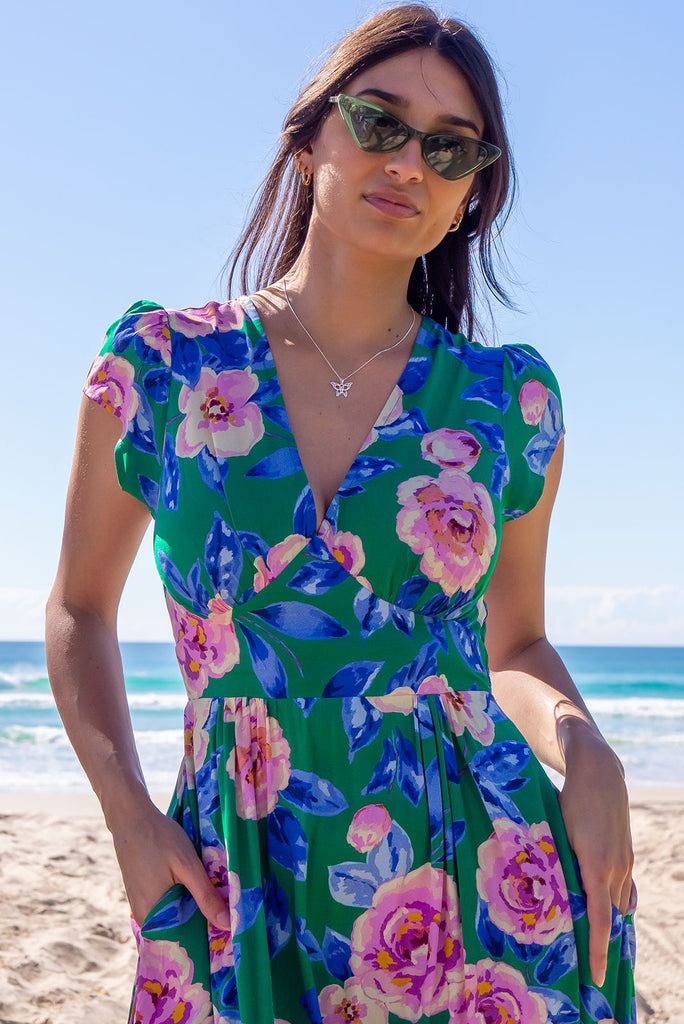 The Lizzie Green Tambourine Dress is a gorgeous green midi dress with a large retro floral print. The dress features cap sleeves, a deep v neckline, fitted Basque waist with gathered bust, elastic shirring at back waist, side pockets and is made from woven 100% rayon.
