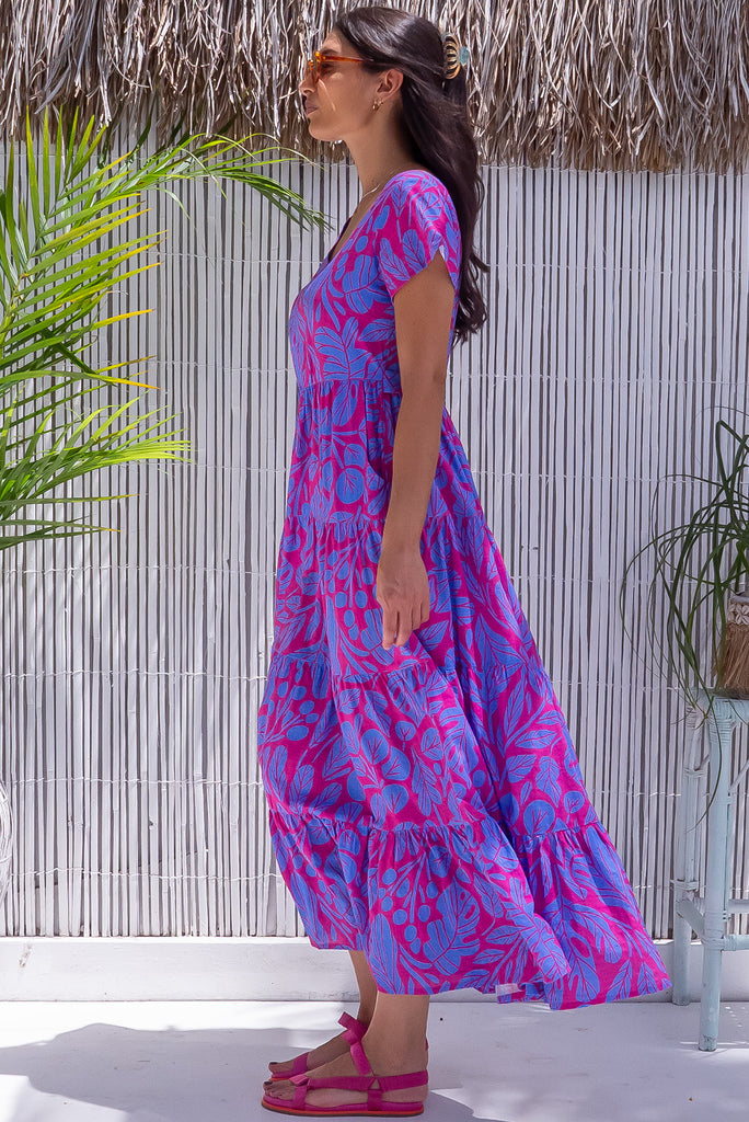 The Lucky Lulu Botany Bloom is a gorgeous hot pink dress with a tonal periwinkle botanical silhouette print. The dress features a wide neckline, was it tabs at the back and side pockets. Made from a woven blend of cotton and rayon.