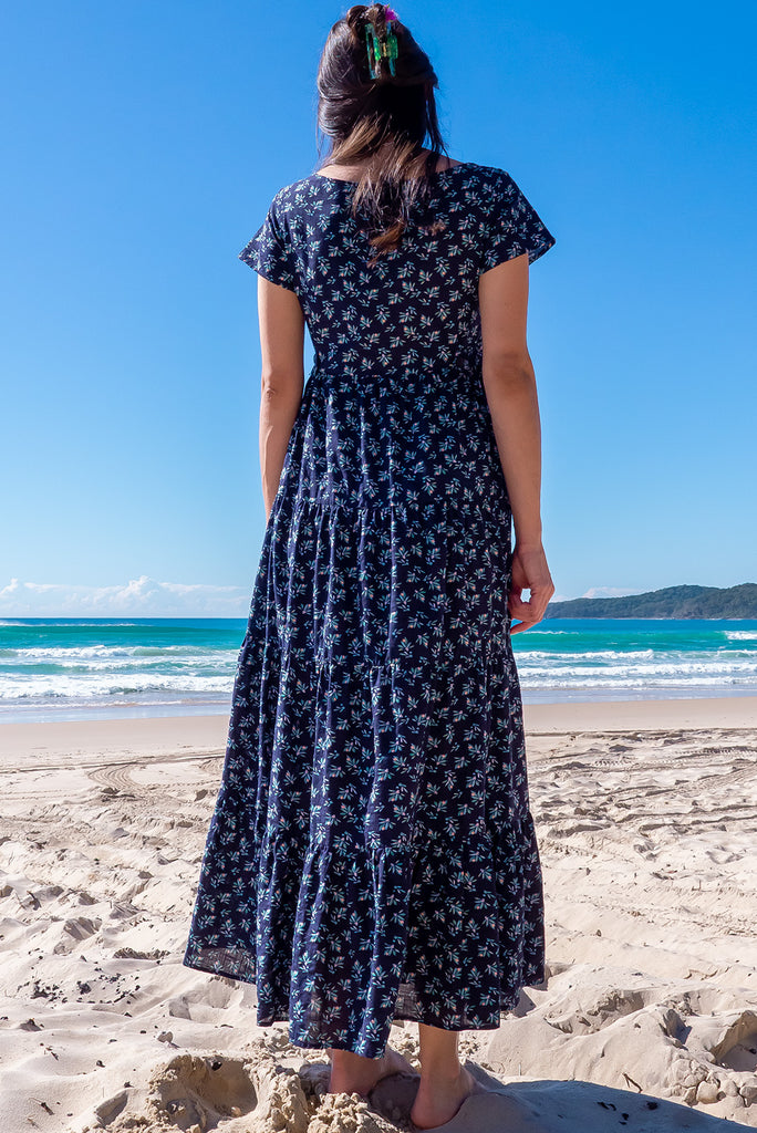 The Lucky Lulu Inky Sprinkle Maxi Dress is a beautiful tiered maxi dress with a navy blue base and small white floral print. This dress features a scooped neckline, adjustable waist tabs, side pockets and a wide tiered skirt. Made a woven blend of cotton and rayon.