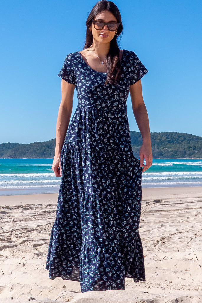 The Lucky Lulu Inky Sprinkle Maxi Dress is a beautiful tiered maxi dress with a navy blue base and small white floral print. This dress features a scooped neckline, adjustable waist tabs, side pockets and a wide tiered skirt. Made a woven blend of cotton and rayon.