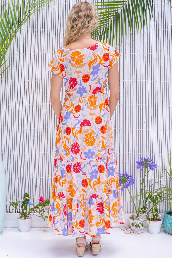 The Lucky Lulu Mediterranean Gold Maxi Dress is a gorgeous cream based maxi dress with a large mediterranean print in shades of orange, red, and periwinkle. This dress features a scooped neckline, adjustable waist tabs, side pockets and a wide tiered skirt. Made from a woven blend of cotton and rayon.